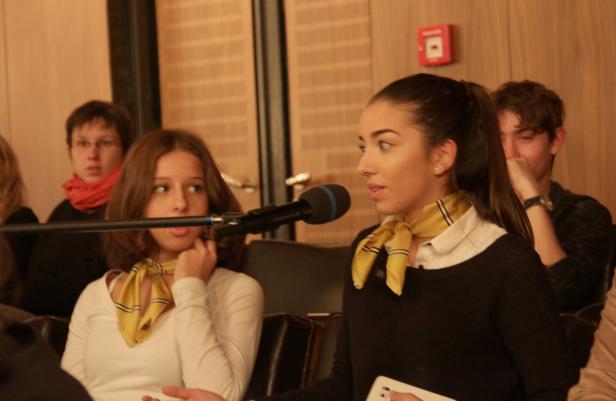 Zwei junge Frauen sprechen in Mikrofone vor Publikum.