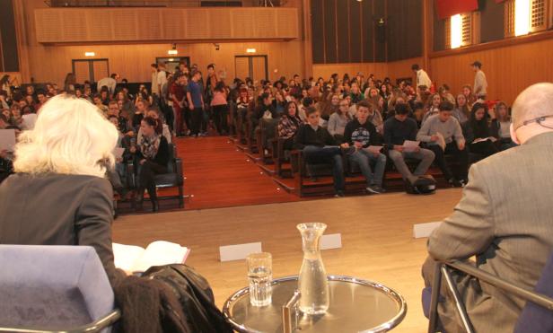 Ein Publikum sitzt in einem Hörsaal und lauscht einem Vortrag.
