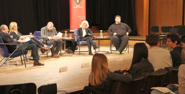 Eine Podiumsdiskussion mit mehreren Personen vor Publikum auf einer Bühne.