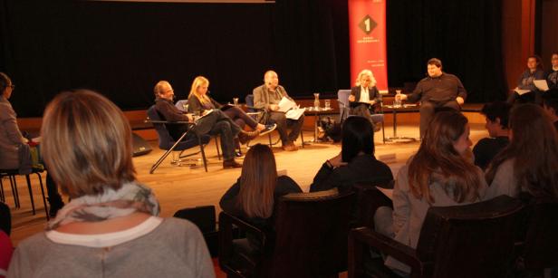 Eine Podiumsdiskussion mit mehreren Personen auf einer Bühne vor Publikum.