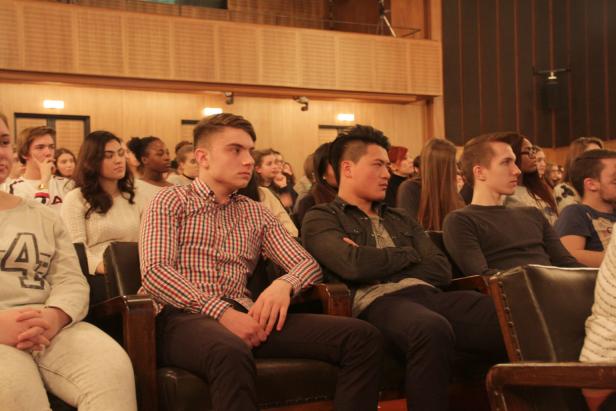 Zuschauer sitzen in einem Auditorium und schauen aufmerksam zu.