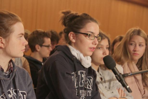 Eine junge Frau spricht bei einer Veranstaltung in ein Mikrofon.