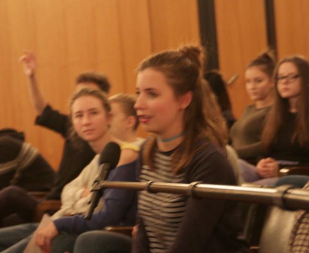 Eine junge Frau spricht während einer Veranstaltung in ein Mikrofon.