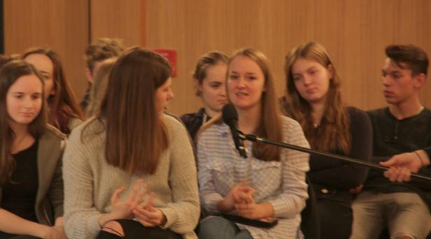 Eine junge Frau spricht bei einer Podiumsdiskussion in ein Mikrofon.