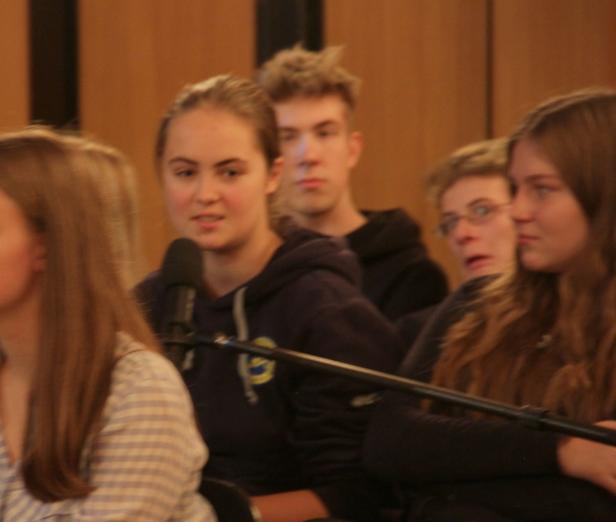 Eine Gruppe junger Leute sitzt aufmerksam bei einer Veranstaltung.