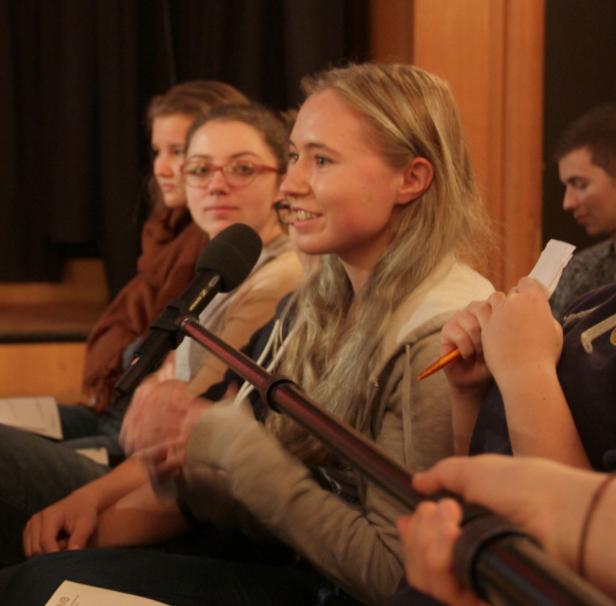 Eine junge Frau spricht während einer Podiumsdiskussion in ein Mikrofon.