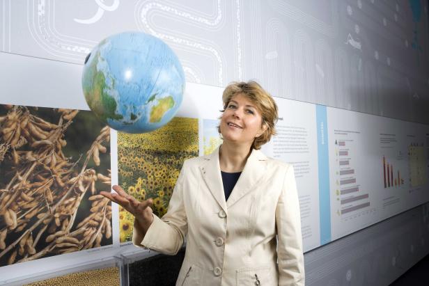 Eine Frau präsentiert einen Globus vor Postern über Biodiesel und Nutzpflanzen wie Soja und Sonnenblumen.