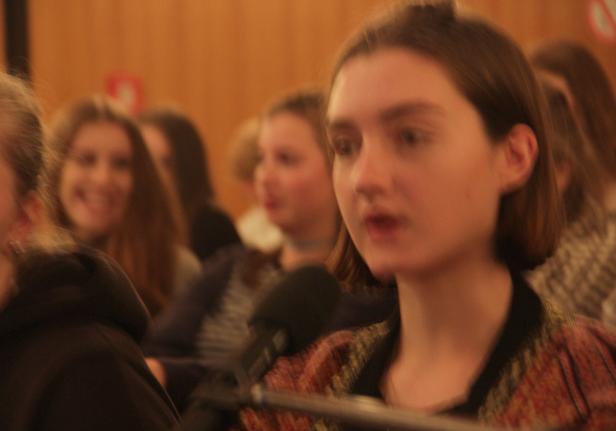 Eine junge Frau spricht während einer Veranstaltung in ein Mikrofon.