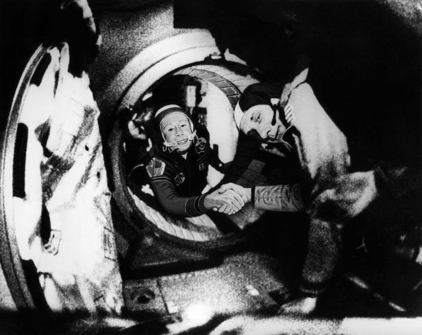 Zwei Astronauten reichen sich in einer Raumstation die Hand.