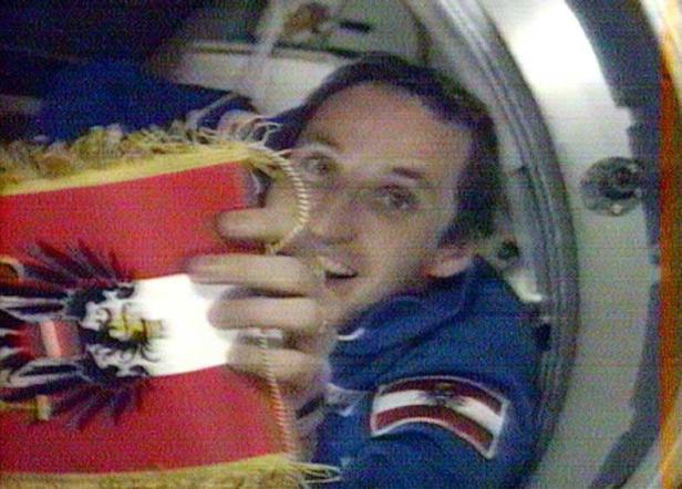 Ein Astronaut im Raumschiff mit einer österreichischen Flagge.