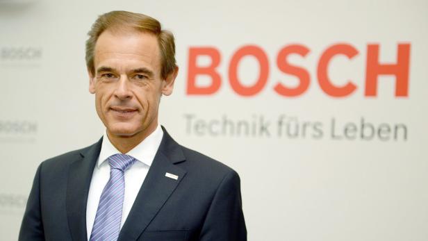 Ein Mann im Anzug steht vor einem Bosch-Logo.