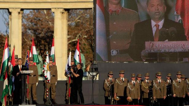 Viktor Orbán hält eine Rede vor ungarischen Flaggen und Militärangehörigen.