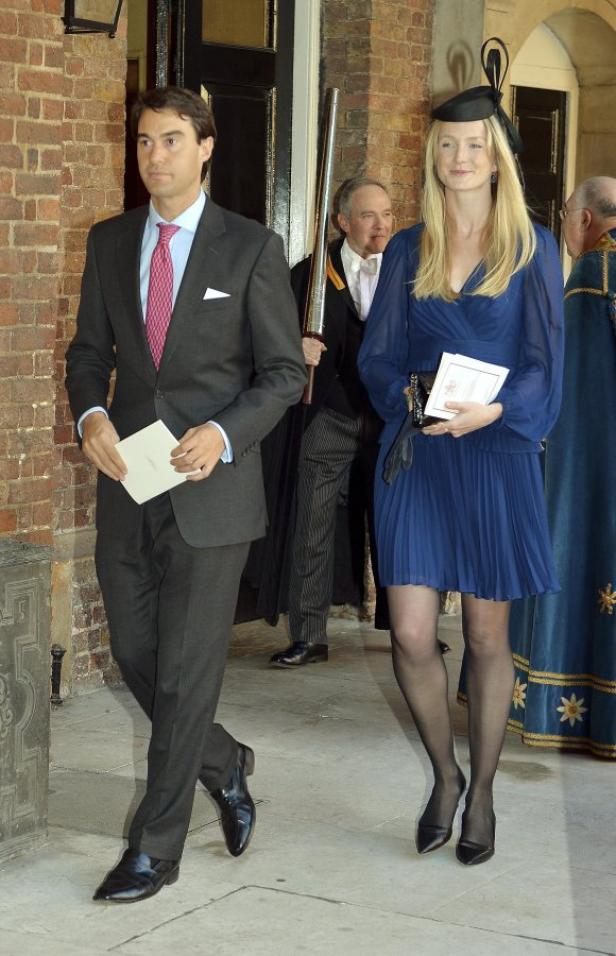 Ein Mann im Anzug und eine Frau im blauen Kleid verlassen ein Gebäude.