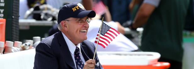 Ein lächelnder Mann mit New York Cap hält eine amerikanische Flagge.