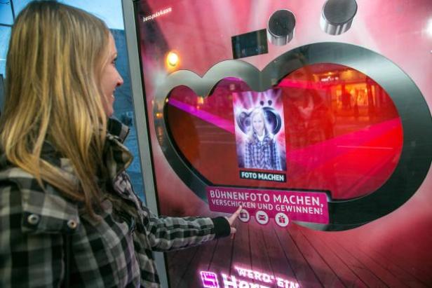 (c: epamedia) Eine Frau bedient einen Fotoautomaten, um ein Bühnenfoto zu machen und zu verschicken.