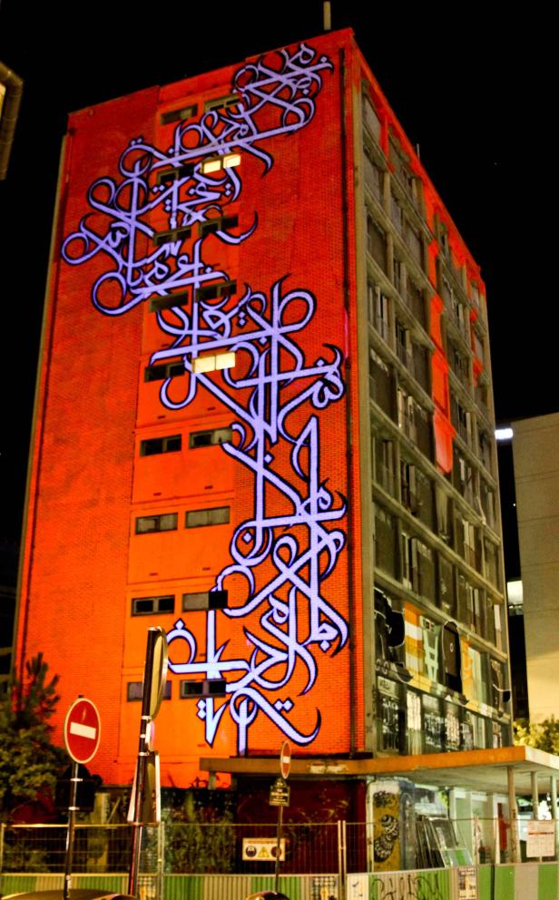 Ein Gebäude mit einem großen Graffiti im arabischen Stil an der Fassade.