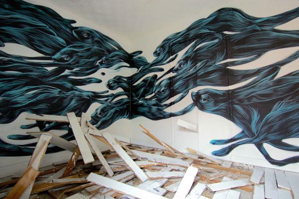 Wandgemälde von stilisierten, blau schattierten Hasen in einem verlassenen Raum.