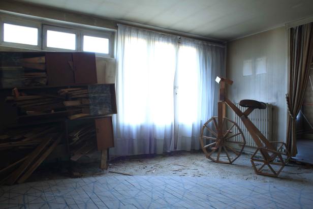 Ein hölzernes Fahrrad steht in einem verlassenen Raum.