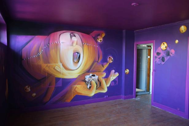 Ein Raum mit einem Wandgemälde einer schreienden Figur, die einen Schädel in der Hand hält.