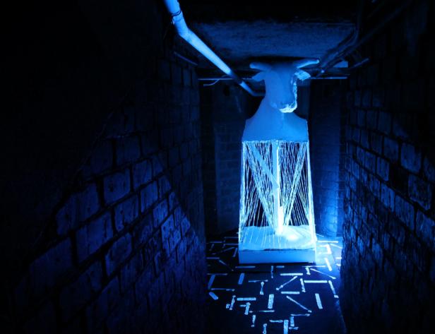 Eine Installation mit einem stilisierten Kuhkopf in einem dunklen Raum mit Backsteinwänden.