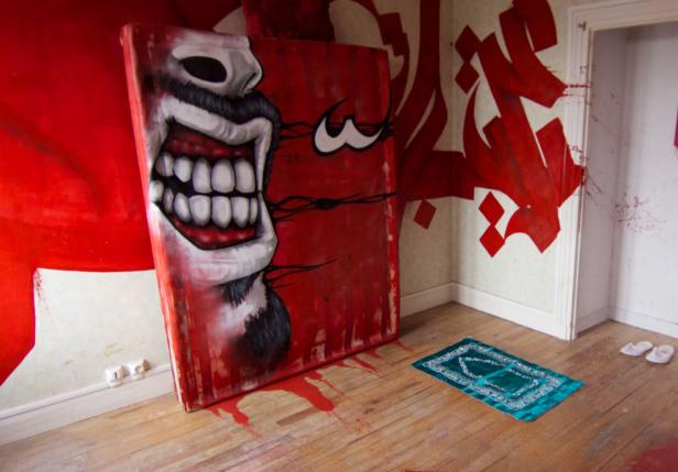 Ein Gemälde mit einem grinsenden Gesicht steht in einem Raum mit roter Graffiti-Kunst.