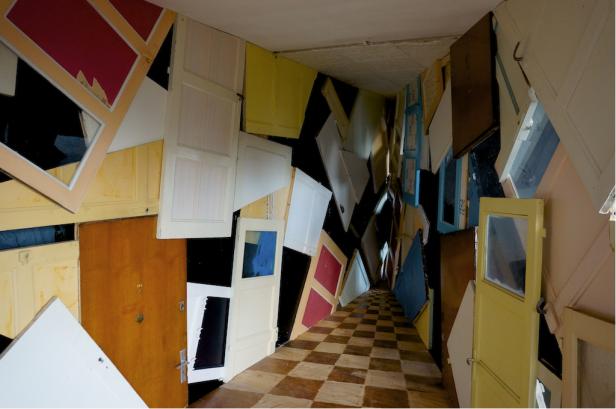 Ein Gang, dessen Wände und Decke mit alten Türen verkleidet sind.