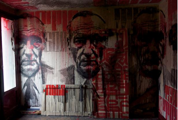 Ein Raum mit Porträt-Graffiti von älteren Männern in Rot- und Schwarztönen.