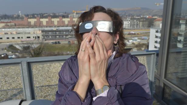 Eine Frau mit spezieller Brille beobachtet eine Sonnenfinsternis.