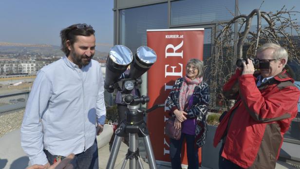 Eine Gruppe von Menschen beobachtet mit einem Spezialteleskop die Sonnenfinsternis.
