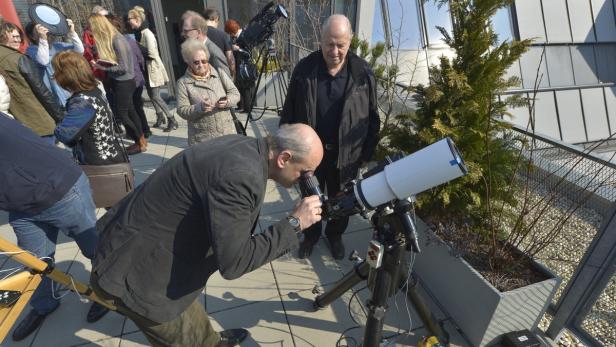Eine Gruppe von Menschen beobachtet mit Teleskopen den Himmel.