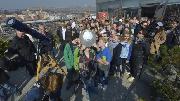 Eine Gruppe von Menschen beobachtet mit Teleskopen und einem Spiegel die Sonnenfinsternis.