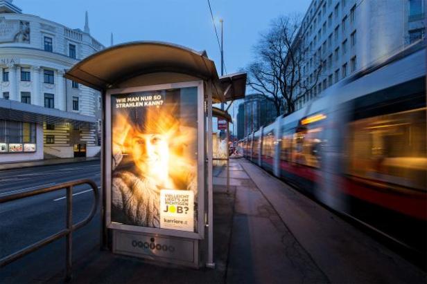 (c: gewista) Eine Bushaltestelle mit Werbung für Karriere.at und einer vorbeifahrenden Straßenbahn.