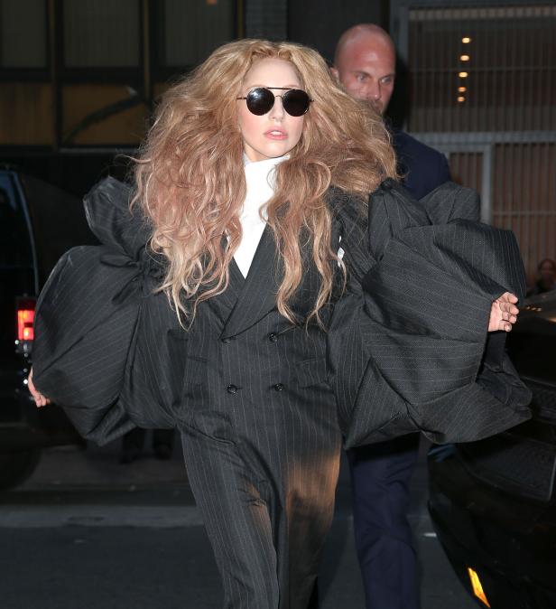 Lady Gaga trägt einen übergroßen, gestreiften Hosenanzug und eine Sonnenbrille.