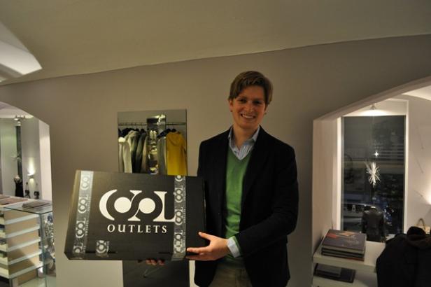 Johannes Meßner, Geschäftsführer von Cool Media und Gründer von CoolOutlets.com, baut die Wertschöpfungskette des Unternehmens im E-Retailing-Bereich aus. (c: cooloutlets.com) Ein Mann hält einen Karton von „Cool Outlets“ in einem Bekleidungsgeschäft.