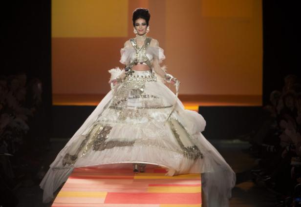 Eine Frau in einem extravaganten, weißen Jean-Paul-Gaultier-Kleid auf einem Laufsteg.