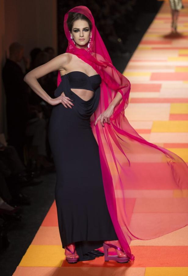 Eine Frau in einem schwarzen Kleid mit pinkfarbenem Schleier auf einem Laufsteg.