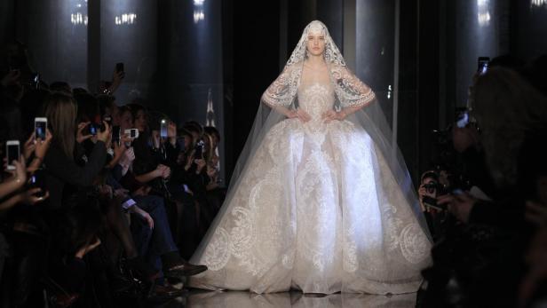 Eine Frau in einem aufwendigen, weißen Brautkleid auf dem Laufsteg.