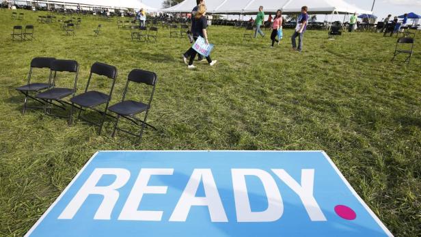Eine Wiese mit Stühlen und einem Schild mit der Aufschrift „READY“ im Vordergrund.