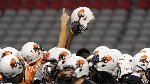 Ein Footballspieler hält seinen Helm der B.C. Lions in die Höhe.