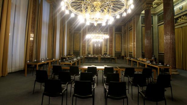 Ein prunkvoller Saal mit Tischen, Stühlen und einem großen Kronleuchter.