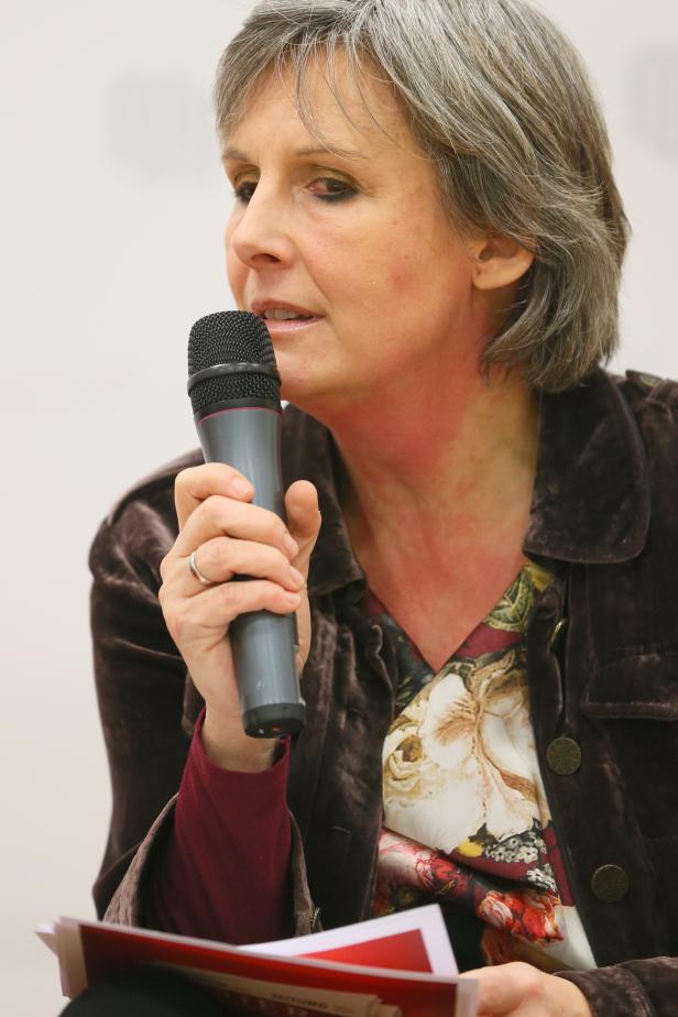 Eine Frau mit grauem Haar spricht in ein Mikrofon.