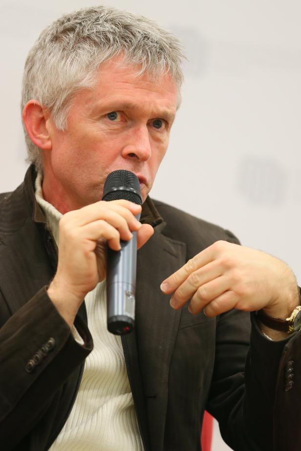 Ein Mann mit grauem Haar spricht in ein Mikrofon.