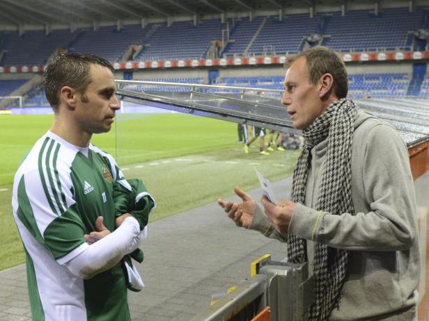Ein Fußballspieler und ein Trainer unterhalten sich am Spielfeldrand.