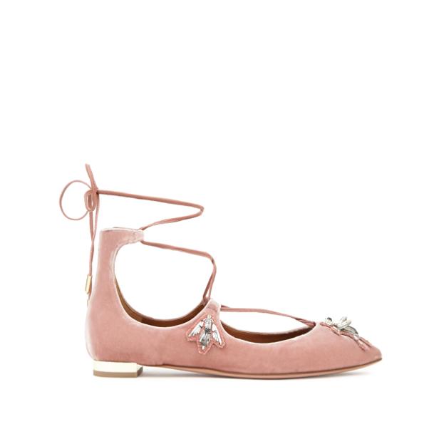 Ein rosafarbener Ballerina-Schuh mit Schnürung und Schmucksteinen auf weißem Hintergrund.