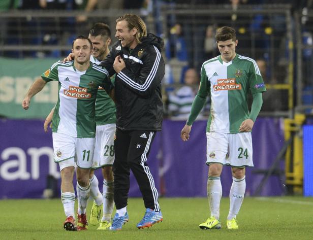 Fußballspieler von Rapid Wien feiern auf dem Rasen.