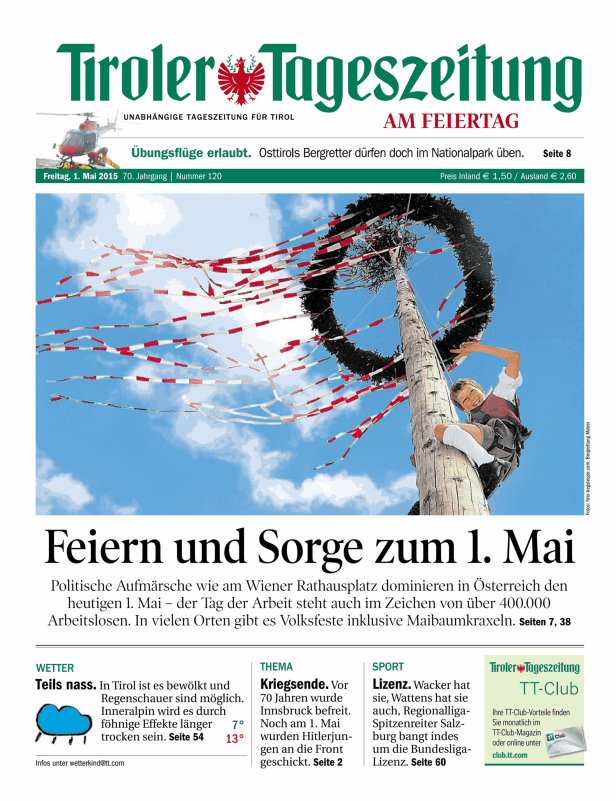 Ein Junge klettert auf einen Maibaum mit rot-weißen Bändern.