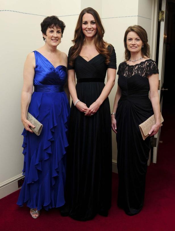 Kate Middleton posiert mit zwei Frauen in Abendkleidern.