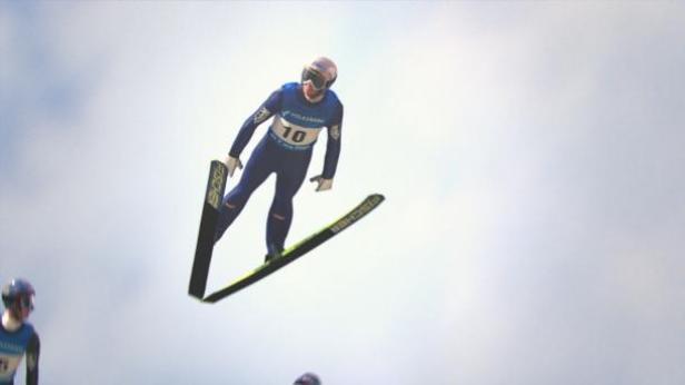 Ein Skispringer mit der Nummer 10 in der Luft.