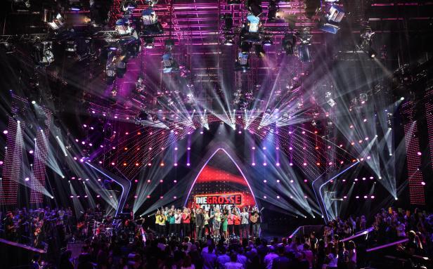 Eine Gruppe von Menschen steht auf einer Bühne vor einem Publikum bei „Die große Chance“.