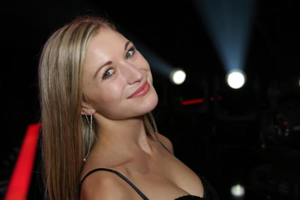 Eine lächelnde Frau mit blonden Haaren und Ohrringen blickt in die Kamera.